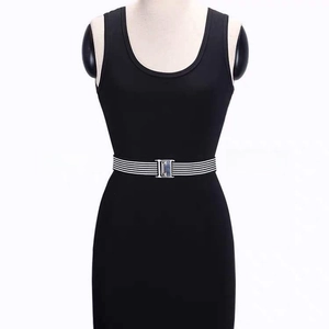 Detail of black and white striped elastic waist belt with silver buckle on a black dress