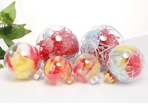 Clear plastic Christmas ornaments filled with colorful feathers and shredded raffia paper