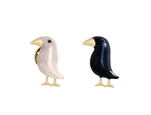 Detailed view of enamel bird brooches in cream and black with golden metallic legs