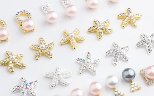 Macro view of starfish-shaped nail art charms with iridescent rhinestones and pearls