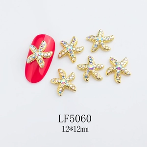 Detailed view of 12x12mm golden starfish nail charm with aurora rhinestones on a red nail