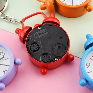 Back view of a mini red alarm clock keychain with adjustment knobs