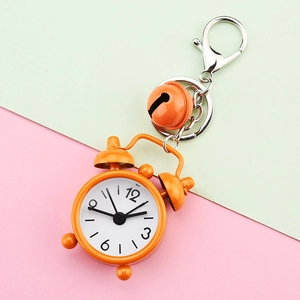 Close-up of orange mini alarm clock keychain with small bell on colorful background