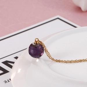 Macro detail of faceted purple crystal sphere pendant on a delicate gold titanium chain