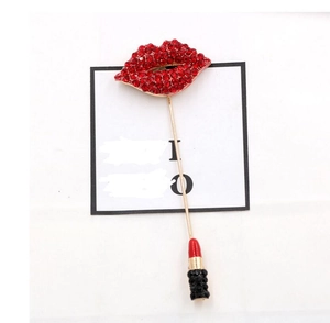 Detail of creative red crystal lip and lipstick brooch with gold finish on card