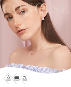 Close-up of S925 silver snowflake earrings and heart necklace on a model with pink backdrop