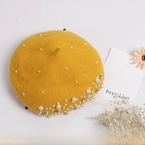 Detailed view of yellow wool felt beret with elegant white pearls and rhinestone accents