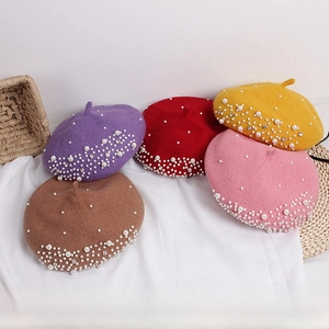 Flat lay of knit wool berets with white pearls and rhinestone gradient in five colors