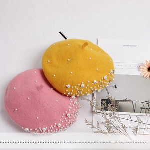 Detail of wool berets with white pearls and rhinestones decoration in pink and yellow