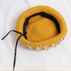 Detail view of yellow wool beret featuring elegant pearls and sparkling rhinestones decoration