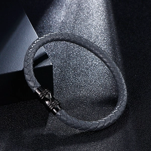 Braided gray leather bracelet with polished black magnetic clasp on dark background