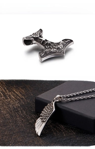Detailed view of Viking Thor's hammer and feather pendants with Norse totem engravings