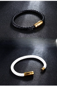 Dettaglio di bracciali in pelle intrecciata bianchi e neri con chiusure magnetiche dorate