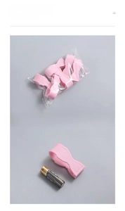 Pink bow-shaped quilt clip shown next to an AA battery for accurate size comparison