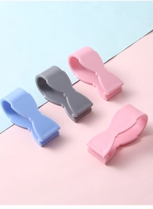 Close-up of bow-shaped duvet clips in pastel blue, gray, and pink on a bicolor background