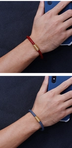 Detail of red and grey-blue braided leather bracelets with gold magnetic clasps