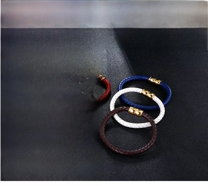 Close-up of assorted braided leather bracelets with gold magnetic clasps on dark background