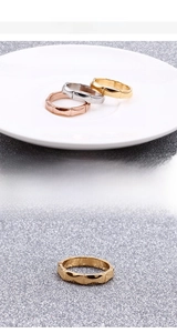 Detail von Bambus-Gelenkringen in Gold, Silber und Roségold auf einem weißen Keramikteller
