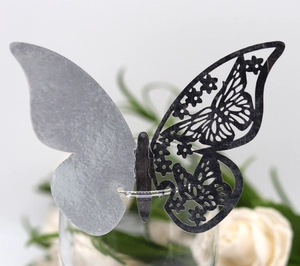 Detail of silver laser-cut butterfly place card with intricate patterns for wine glass decor