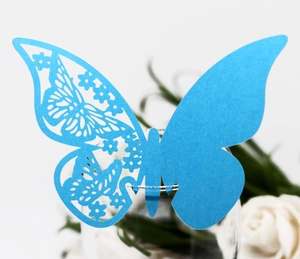 Close-up of laser-cut blue butterfly paper place card on a wine glass rim