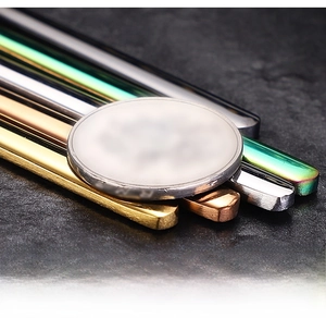 Macro detail of thickened stainless steel spoons in five colors next to a reference coin