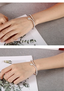 Close-up of silver snake wrap bracelet with green stone eyes and sparkling crystals