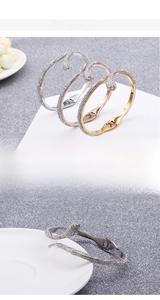 Close-up of 18k gold plated snake bracelet featuring sparkling pavé crystals and green eyes