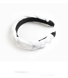 Detailed close-up of a braided black and white velvet headband with woven texture