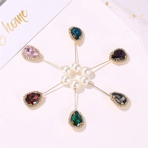 Close-up of teardrop crystal brooches set with rhinestones and elegant pearls