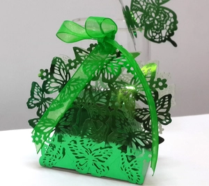 Detail of laser-cut butterfly wedding favor box with shiny green paper and satin ribbon