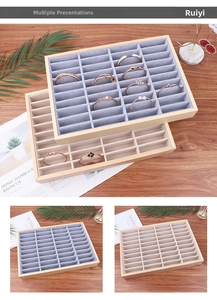 Macro view of wooden jewelry display tray with grey velvet compartments for rings