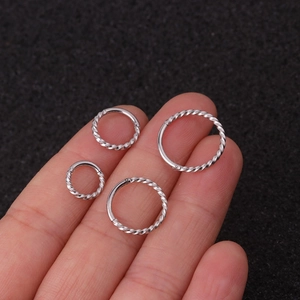 Set of four silver twisted stainless steel earrings shown on hand with a textured background