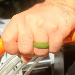 Close-up of olive green silicone sports ring with Greek key pattern on a male hand