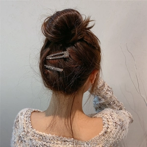 Détail de deux pinces à cheveux en cristal argenté sur un chignon de femme