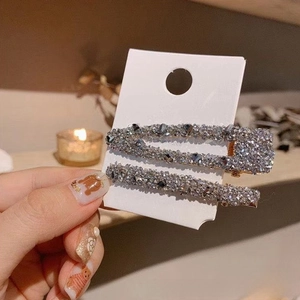 Détail de pinces à cheveux en cristal gris sur carte dans une ambiance lumineuse douce