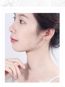 Close-up of sparkling heart-shaped stud earrings featuring bicolor zircon on model's ear