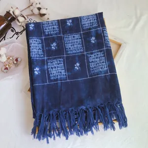 Macro detail of indigo tie-dye checkered scarf with traditional floral patterns and tassels