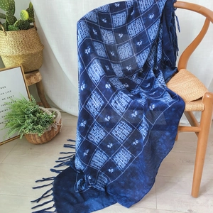 Blue tie-dye checkered scarf with long tassels draped on a chair for travel decor