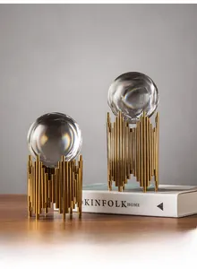 Close-up of modern clear crystal balls with artistic golden metal cage stands on dark wood