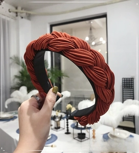 Detail of orange braided fabric headband featuring pleated texture and wide knotted design