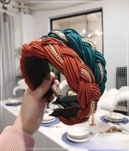 Dettaglio del cerchietto a treccia in tessuto a pieghe con catena in metallo dorato lucido