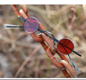 Steampunk round red lens sunglasses hanging on rusty iron chain for vintage industrial style