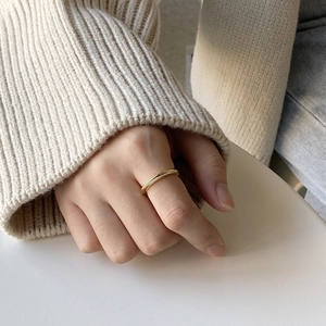 Close-up of a minimalist gold cone ring on finger with soft knit sweater background