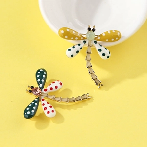 Detailed top view of colorful dragonfly brooches with polka dots on a bright yellow backdrop