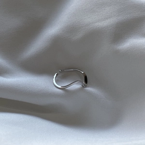 Minimalist S925 sterling silver Mobius ring with wavy curve design on white fabric