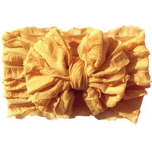 Macro detail of bright yellow baby headband with large ruffled lace texture bow