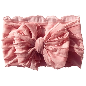 Detailed view of pink baby headband with large lace trim bow and soft pleated fabric