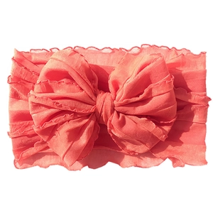 Detail of coral lace baby headband featuring large layered bow and elastic fabric