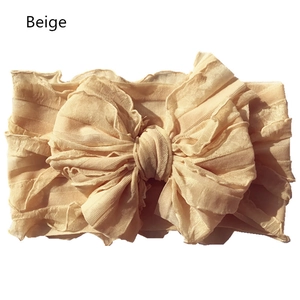Detailed view of beige ribbed fabric headband featuring a large bow with ruffled edges