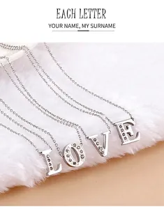 Macro shot of silver LOVE initial pendants with crystals on a soft plush background